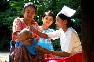 A health care provider gives an infant the polio drop in Burma