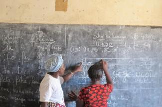 Two individuals write on a chalkboard