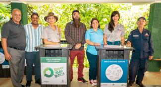 USAID and community members pose for a picture with waste containers