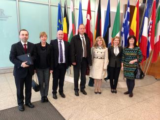 Group of businessmen and women stand in front of colorful flags