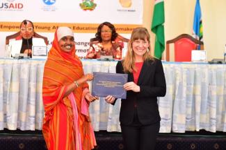 USAID/KEA Education Development Officer, Brooke Estes, presents a certificate to a participant at the commencement ceremony of the Education Changemakers cohort at Kenyatta University. In the background are Pitsto Mpolokeng, of Trevor Noah Foundation (left) and Prof. Waceke Wanjohi, Acting Vice Chancellor, Kenyatta University (right).