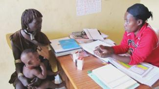 Tarikua Lulayehu, right, a health extension worker at the Aera Keysa health post in the Hamer woreda in Ethiopia, assesses and treats 8-month-old Bora Shewki for pneumonia.