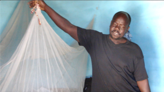 : Mr Mahamat stands proudly in front of a bed net, committed to consistently preventing malaria in his household in Guider, Far North Cameroon. Photo credit: Christelle Ngueajio, DOC USAID.