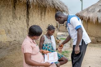 A Physician Assistant/Network Leader supports a community health officer following up with a referred client at home.