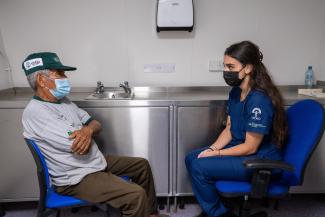 A young psychologist woman counseling an old man in a hospital ship