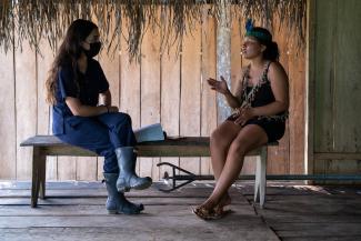 Young psychologist woman talking to a young indigenous woman in her house