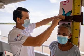 Doctor measuring standing height of an indigenous old woman