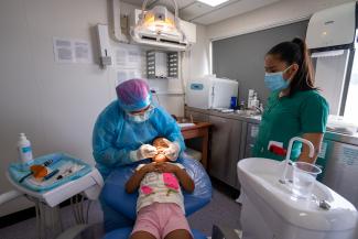 Dentist tending to an indigenous girl resting on a dental couch