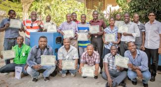 A group photo of trainees holding their certificates after completing their training.