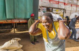 A woman carries a sack on her back