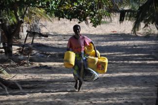 Rehema Ngowa collects water from the newly rehabilitated well in her community