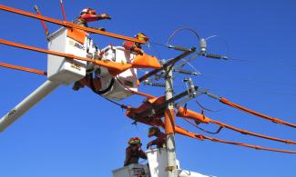 Two people working on electrical lines