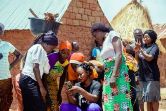 A field officer with Thrive Agric, a Nigeria-based Trade Hub partner, shows farmers how to use apps that allow them to easily send, receive, save, and borrow money. 