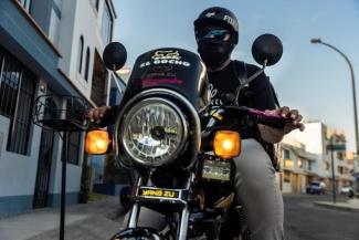 A man on a motorcycle delivering bread and other bakery goods