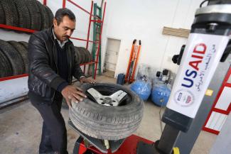 Abdullah Sharari, owner of a tire fixing station in Irbid, stands behind a tire changing machine in his new shop 