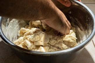 A hand mixing the dough within a metal bowl.