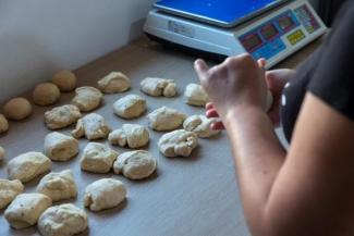 A woman in the kitchen shaping the bread loaves.