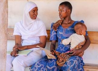 Nurse Jalia Rwinza sits with a mother and her child