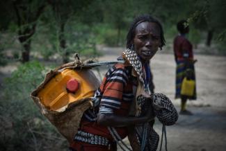 A woman in Ethiopia transports her water container back to her home after filling it at a pumping station in her locale. Photo credit: AECOM.