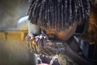 A woman takes a drink from a water pump built by a USAID water and sanitation project in Era, Ethiopia. In 2017, USAID provided safe drinking water for more than 300,000 people. Photo credit: AECOM.