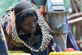 A woman fills her containers with water from a pump built by a USAID water and sanitation project in Era, Ethiopia. Photo credit: AECOM.