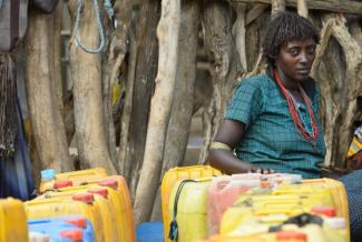 A woman waits at a pumping station to fill her water bottles. Photo credit: AECOM.