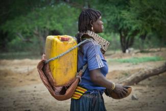 An Ethiopian woman carries her water container back to her home. Photo credit: AECOM.