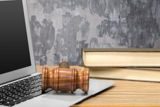 A gavel on a laptop and some books on a desk