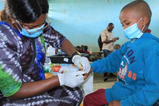 Nurse taking a blood sample from a boy in a clinic.