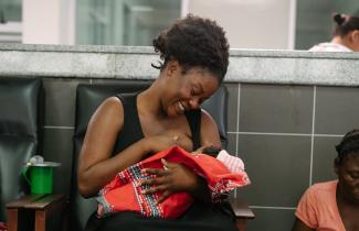 A woman smiling and holding an infant