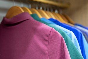 Multiple collared shirts hanging on a bar