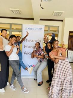 a group of young Rwandans, smiling, energized, lifting their hands up in the air