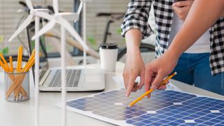 close up view of alternative energy engineer pointing to a solar power panel