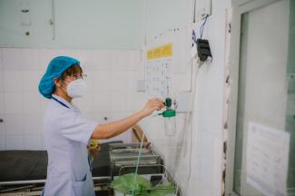 A doctor adjusts a device that supplies oxygen bedside in the hospital.