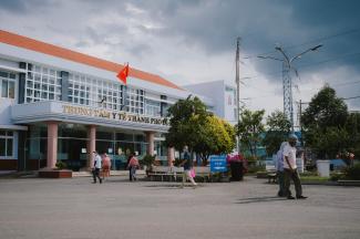 People walk outside of an entrance to a hospital.