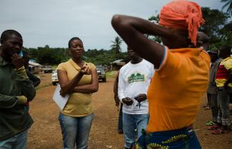 A woman speaks to a group of mourners