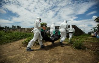 Workers in Hazmat suits carry supplies