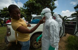 A woman adjusts a workers hazmat suit