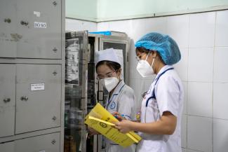 A doctor and nurse speak to each other in a hospital hallway.