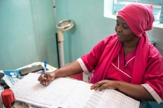 Aissatou Diarra, matron in the health center of Sarre Bilaly, takes a patient’s file out and writes a prescription at her desk in the Kolda region, Senegal.