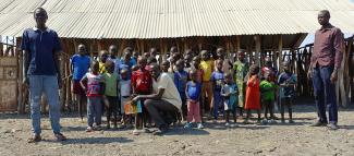 Students and teachers at Nyangore Primary School stand in front of the newly-built learning facility.