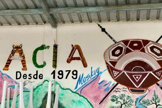 Un muro pintado con el nombre de la organización ACIA y dibujos indígenas