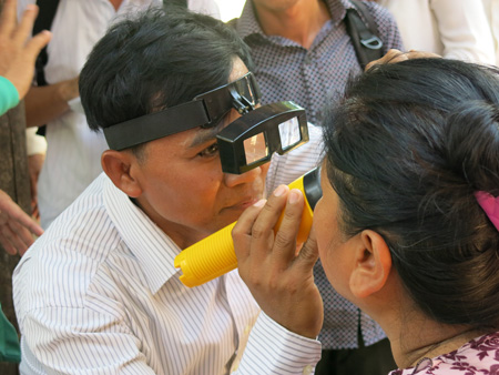 A doctor checks the eyes of a woman in Cambodia