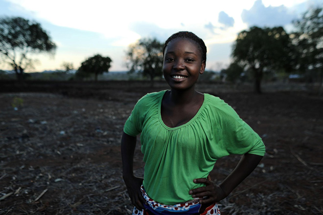 A woman wearing a green shirt smiles at the camera.