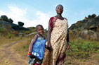 A mother stands with her child who is holding a bednet