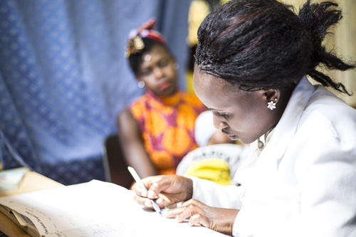 A doctor makes notes while a patient looks on.