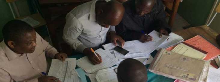 Four men sit around a table and look at papers.